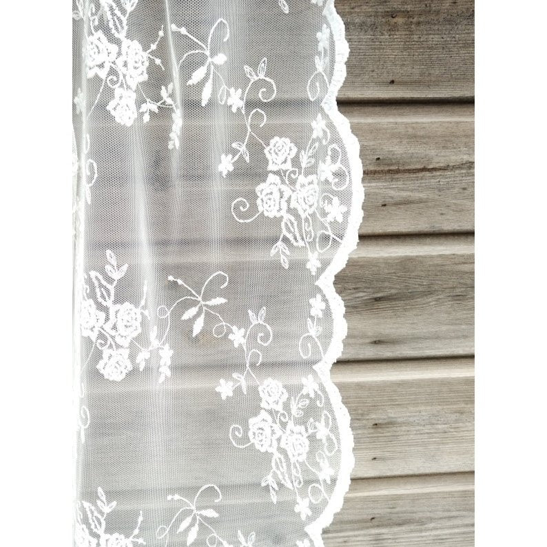 Romantic ambiance created by off-white lace curtain with scalloped borders and cascading velvet.