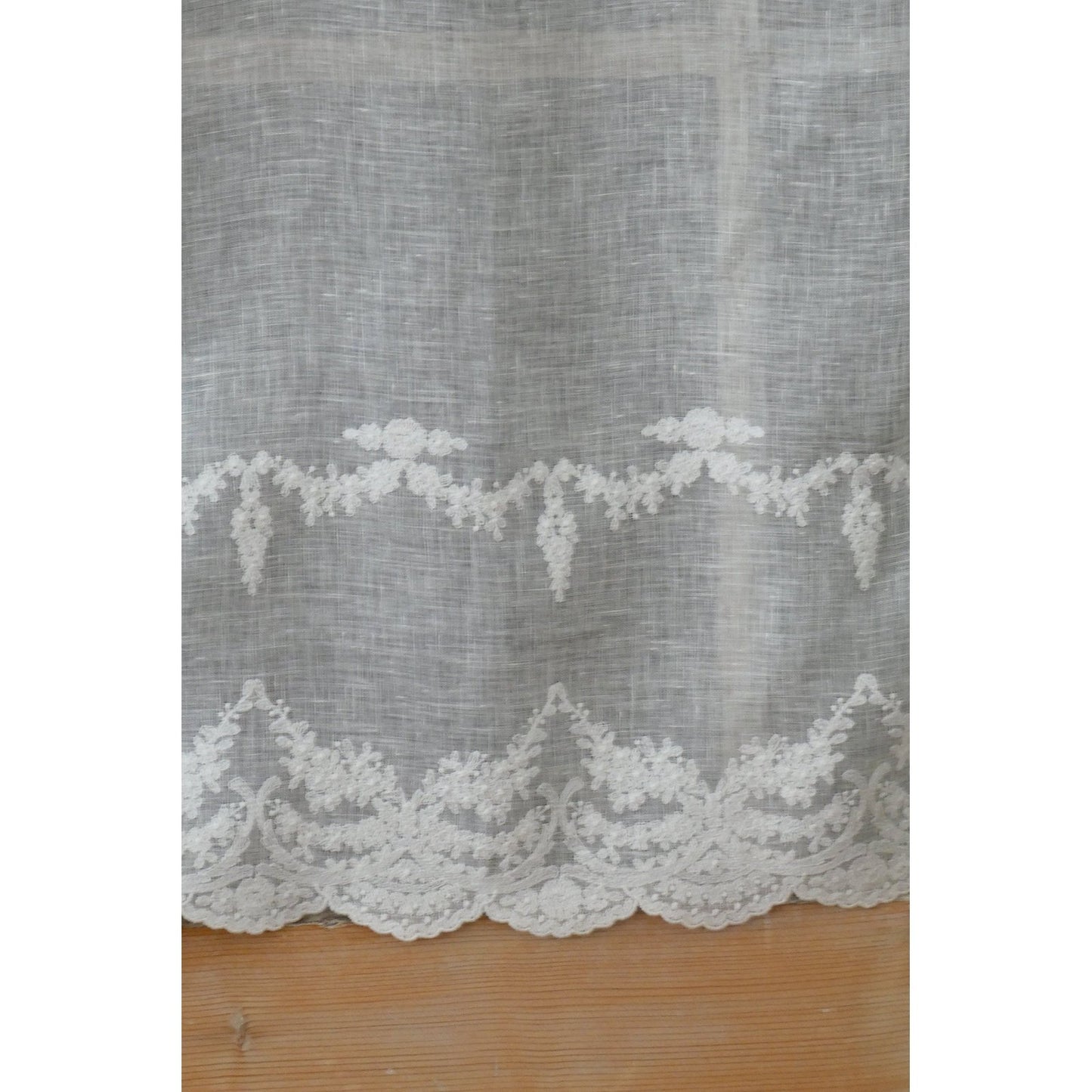 Close-up of embroidered details on off-white linen short curtain.